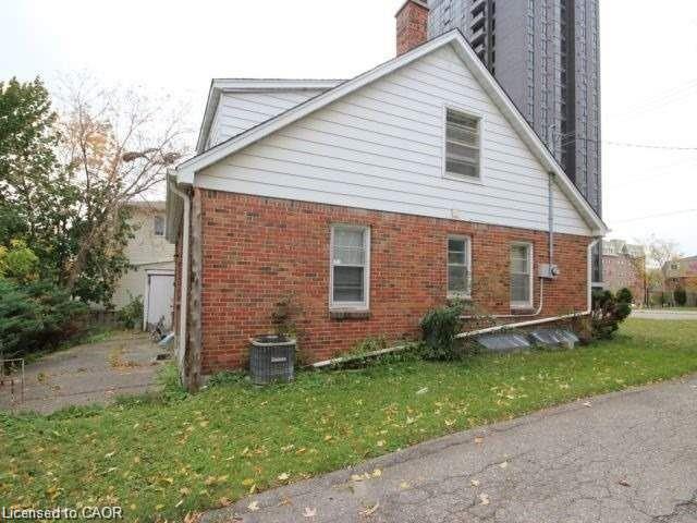 View of home's exterior featuring a chimney, brick siding, and a lawn