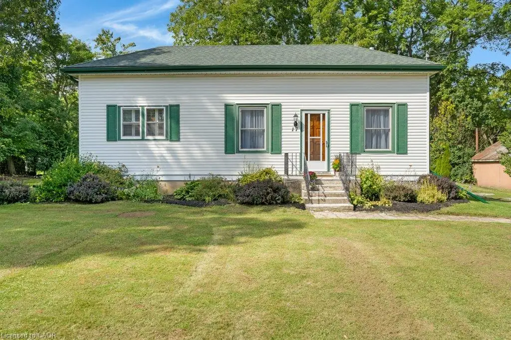 Classic cottage-style home featuring white horizontal siding, a dark green roof, and coordinating green exterior shutters