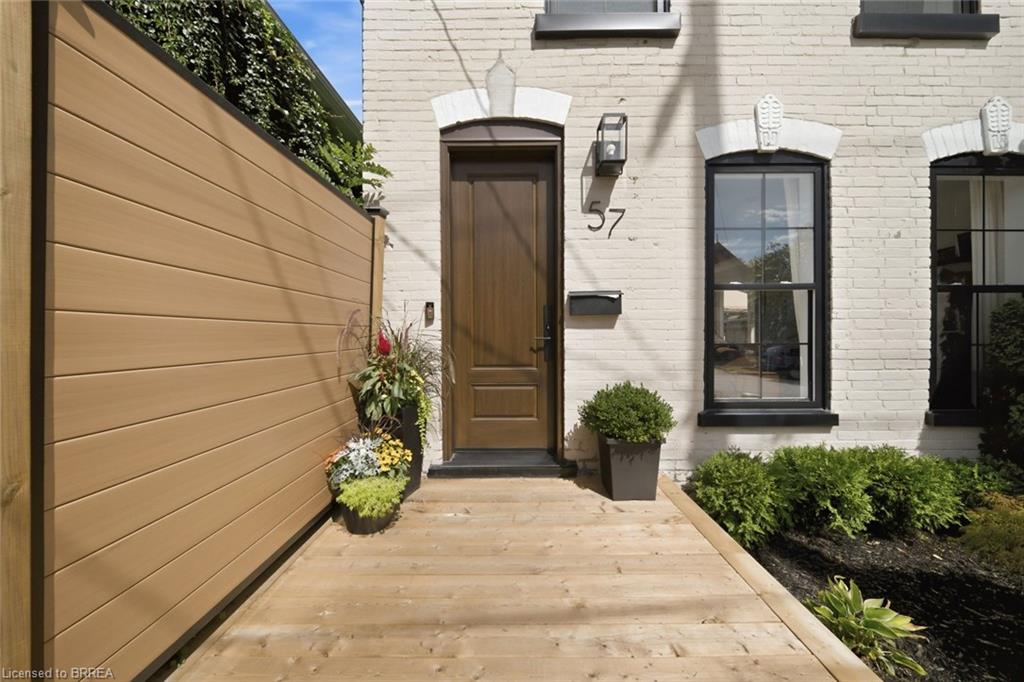 White brick exterior with black framed windows, a solid wood entry door, and wood plank decking