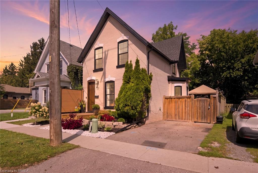 Brick exterior with dark-trimmed windows, a front porch, and a dedicated driveway