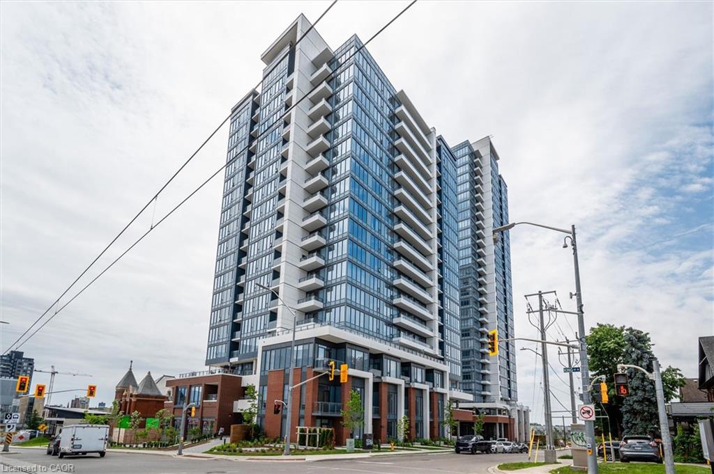 Modern high-rise building featuring extensive glass curtain walls, multiple balconies with glass railings, and a multi-story brick and glass base