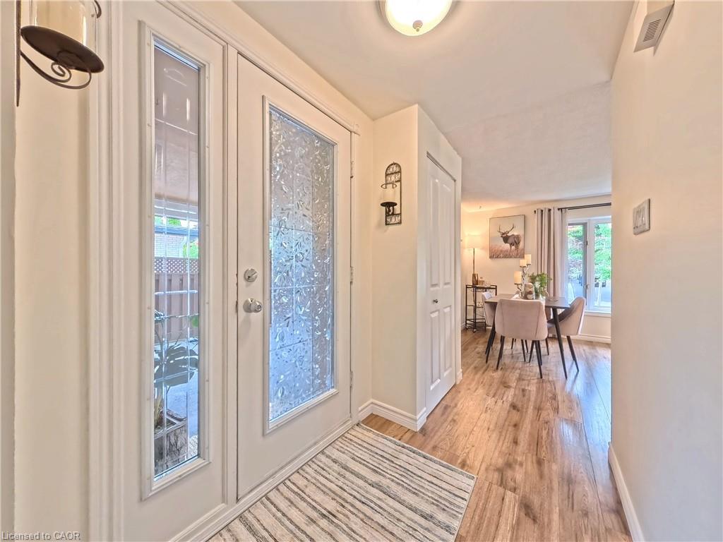 Entryway featuring a double door with decorative glass, wood-finish flooring, and a built-in coat closet