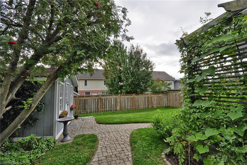 Manicured lawn with a paver pathway, mature trees, and a garden shed