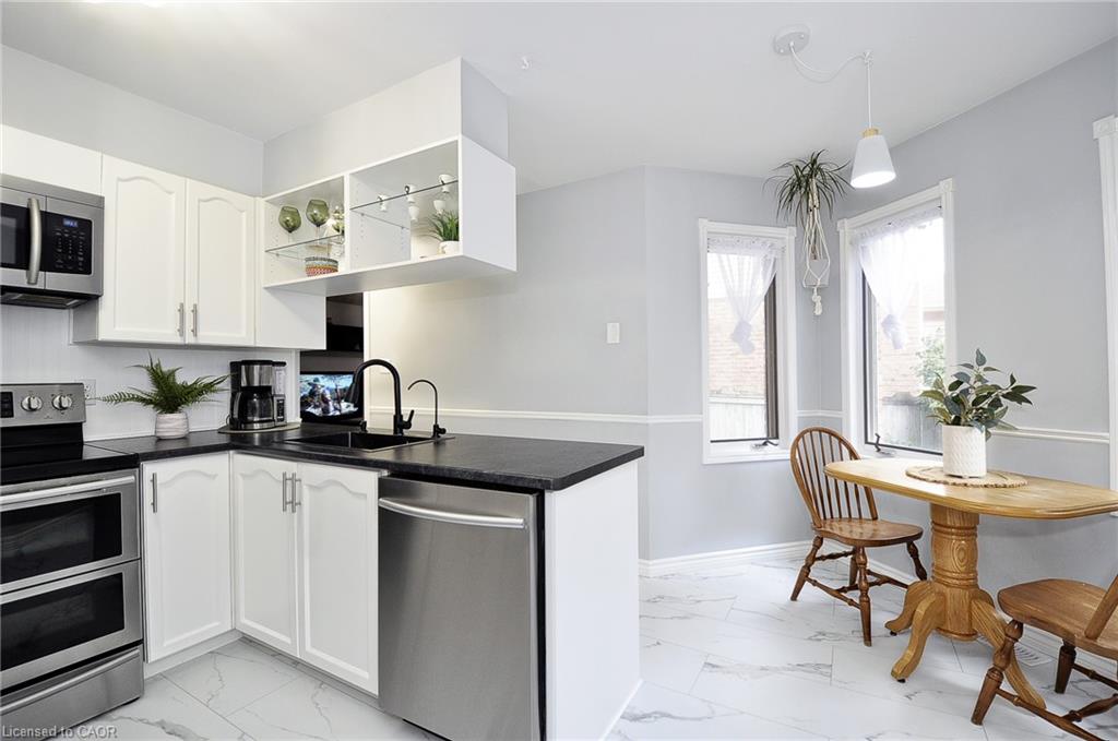 White cabinetry with dark countertops, stainless steel appliances, and a marble-look tile floor