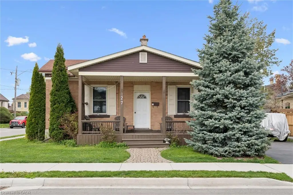 Charming brick colonial with a welcoming front porch, mature evergreen landscaping, and manicured lawn