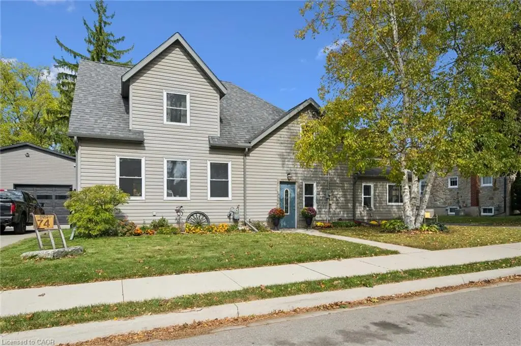Gabled roofline, light gray siding, prominent front yard, paved driveway, detached garage with dark gray siding