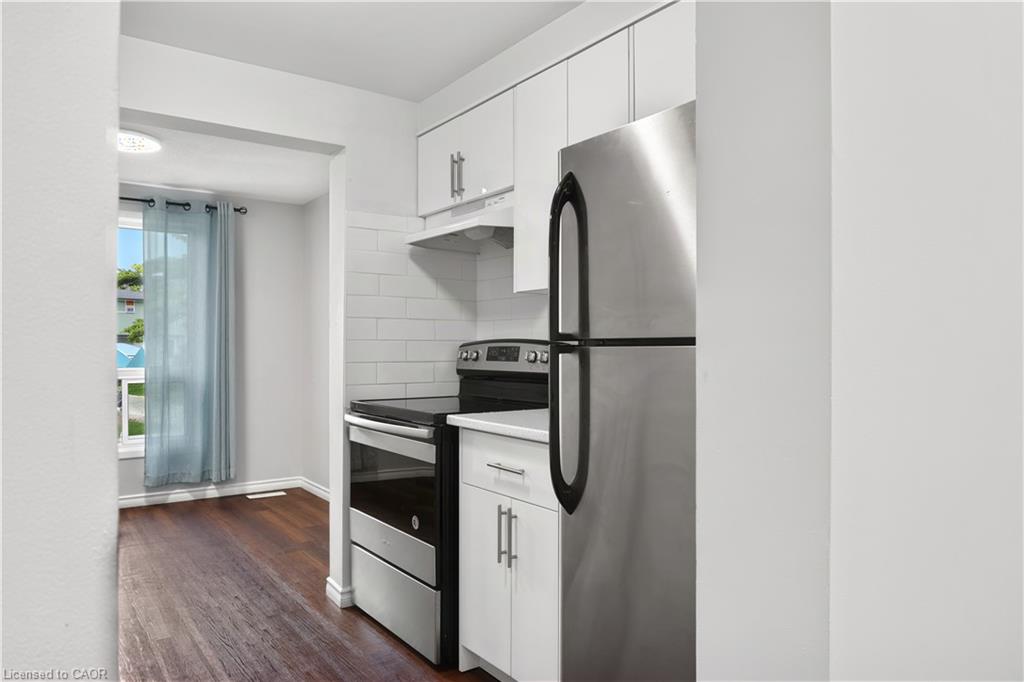 Kitchen featuring white cabinetry, stainless steel appliances, subway tile backsplash, and wood-finish flooring