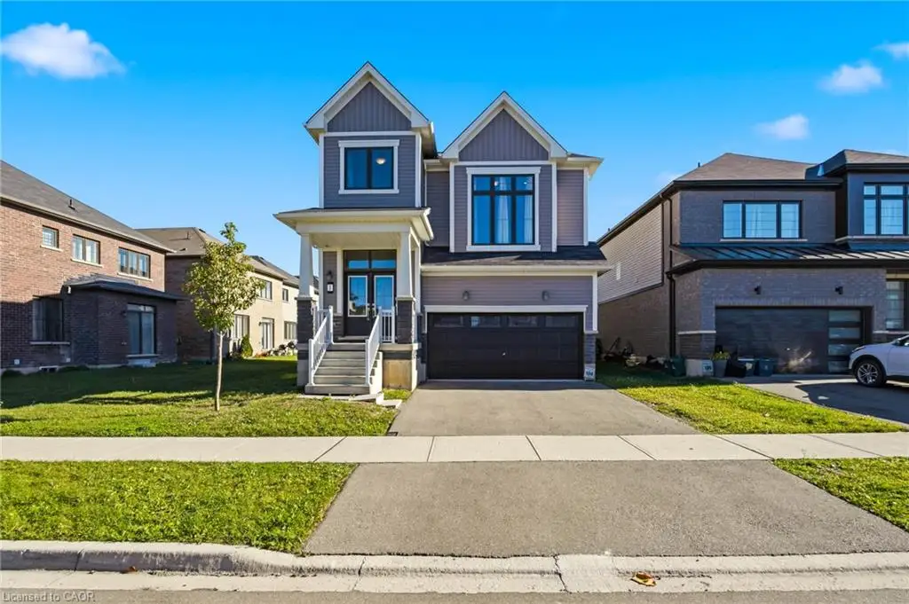Two-story exterior featuring lap siding and stone veneer accents, covered front porch with a pediment, multi-pane windows, and a paved two-car driveway