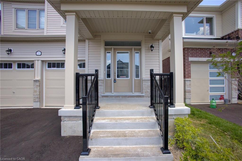 Covered front porch with concrete steps and black iron railings