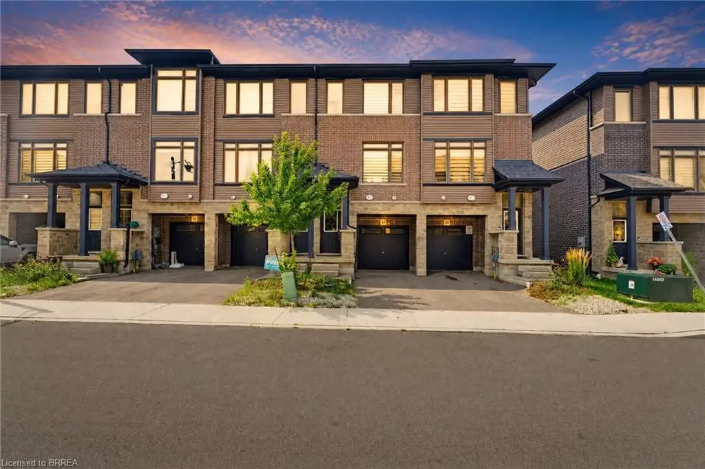 Contemporary townhome exterior featuring brick and siding facade, covered entryways, large windows, and integrated garage doors