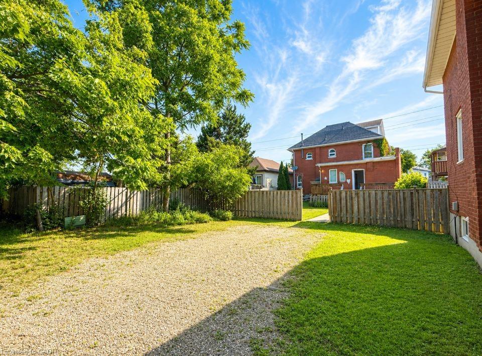 Expansive gravel parking area bordered by a manicured lawn and wooden privacy fencing