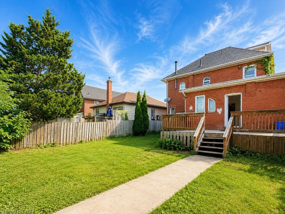 Expansive green lawn with a concrete pathway and privacy fencing