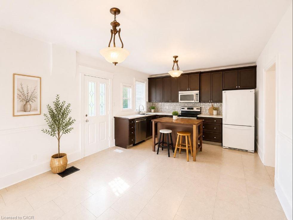 Spacious kitchen and dining area featuring dark wood cabinetry, stainless steel appliances, a patterned tile backsplash, and light-toned tile flooring