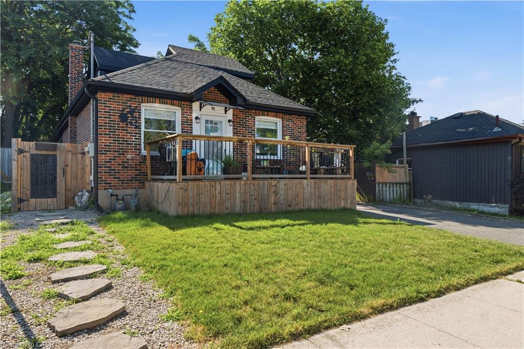 Brick exterior featuring a wood deck with a railing, a stone pathway, a gravel driveway, and a fenced side yard