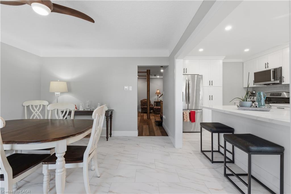Open-concept living area featuring white tile flooring, a kitchen island with seating, recessed lighting, white cabinetry, and stainless steel appliances