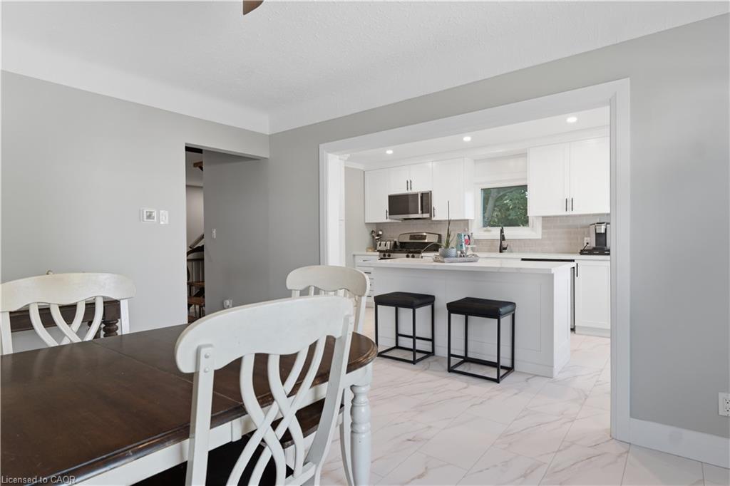 Modern kitchen features white cabinetry, stainless steel appliances, a center island with bar seating, and recessed lighting