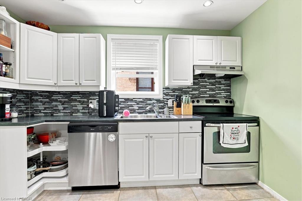 Kitchen featuring white cabinetry, mosaic tile backsplash, stainless steel dishwasher, stainless steel range, and tile flooring