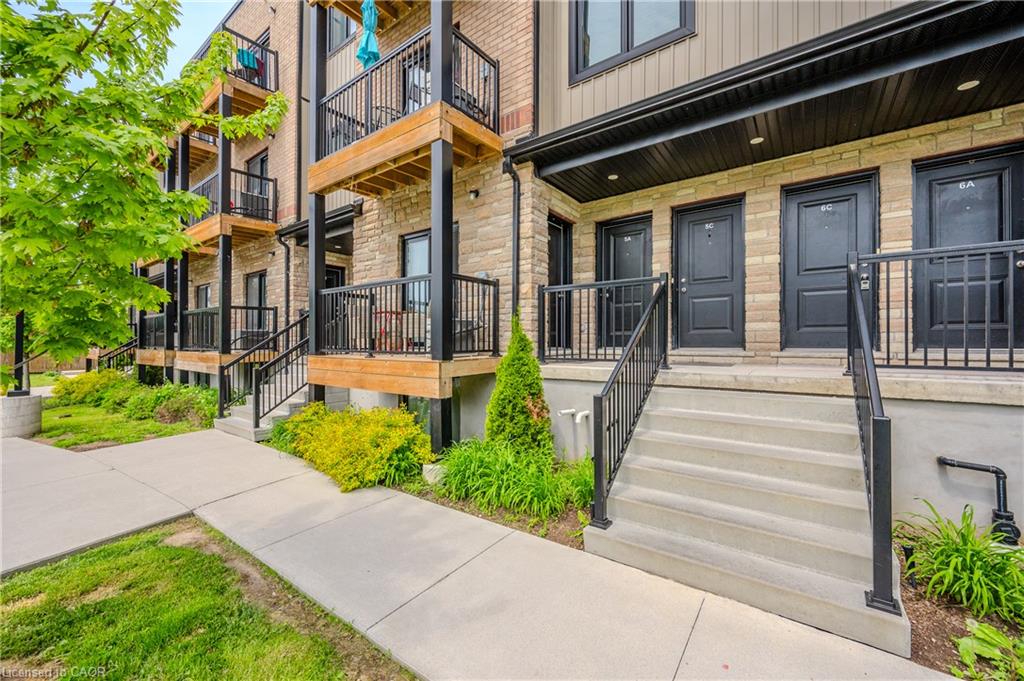 Stone and siding exterior with individual entry doors, concrete stairs, and black metal railings