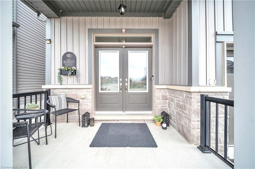 Front entry with double glass panel doors, transom window, stone veneer accents, and vertical siding