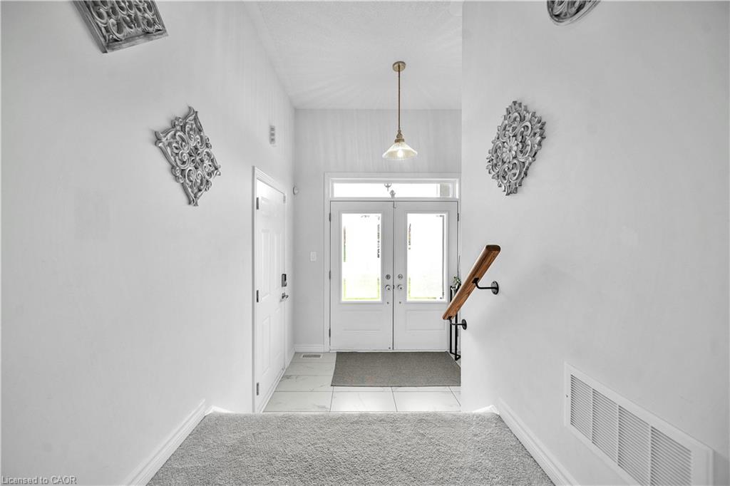 Foyer with ceramic tile flooring, double glass-paneled entry doors, and a suspended pendant light fixture