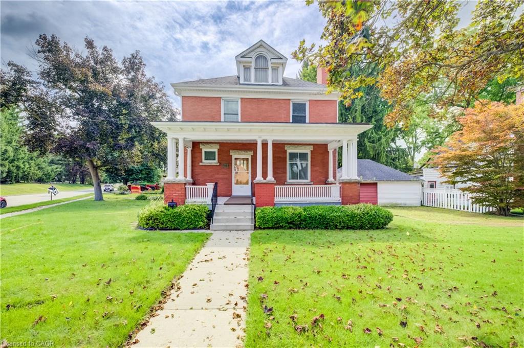 Brick exterior with white columned porch, dormer window, and white picket fence