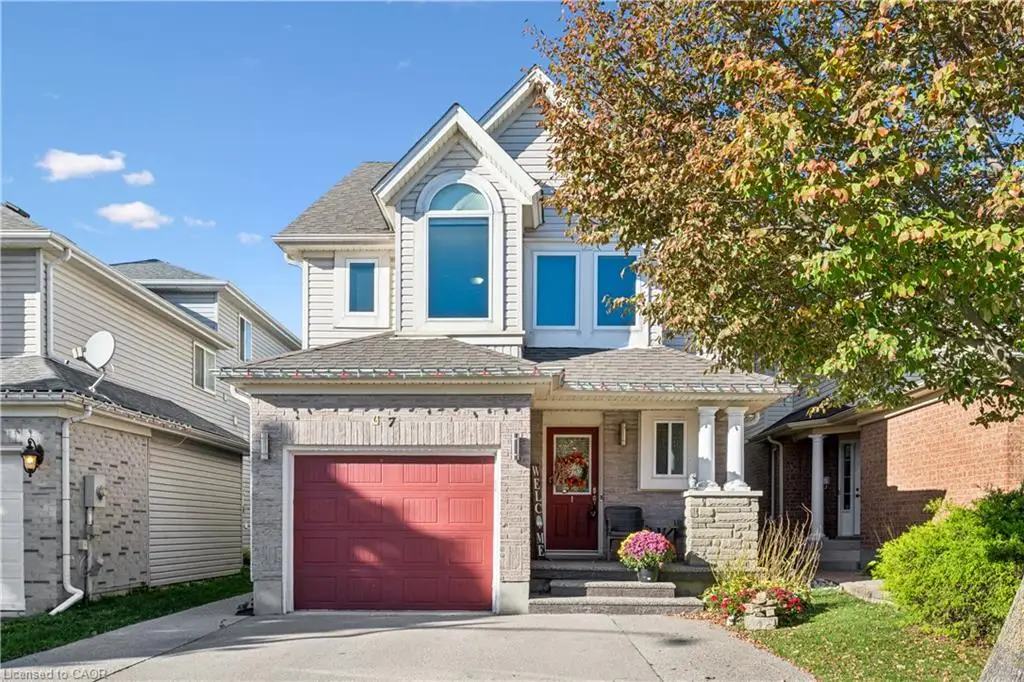 Two-story residence featuring a partial stone facade, attached single-car garage, covered front porch with stone columns, and arched window detailing