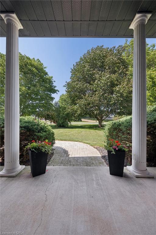Porch with fluted columns and a textured ceiling, opening to a paver walkway and mature trees