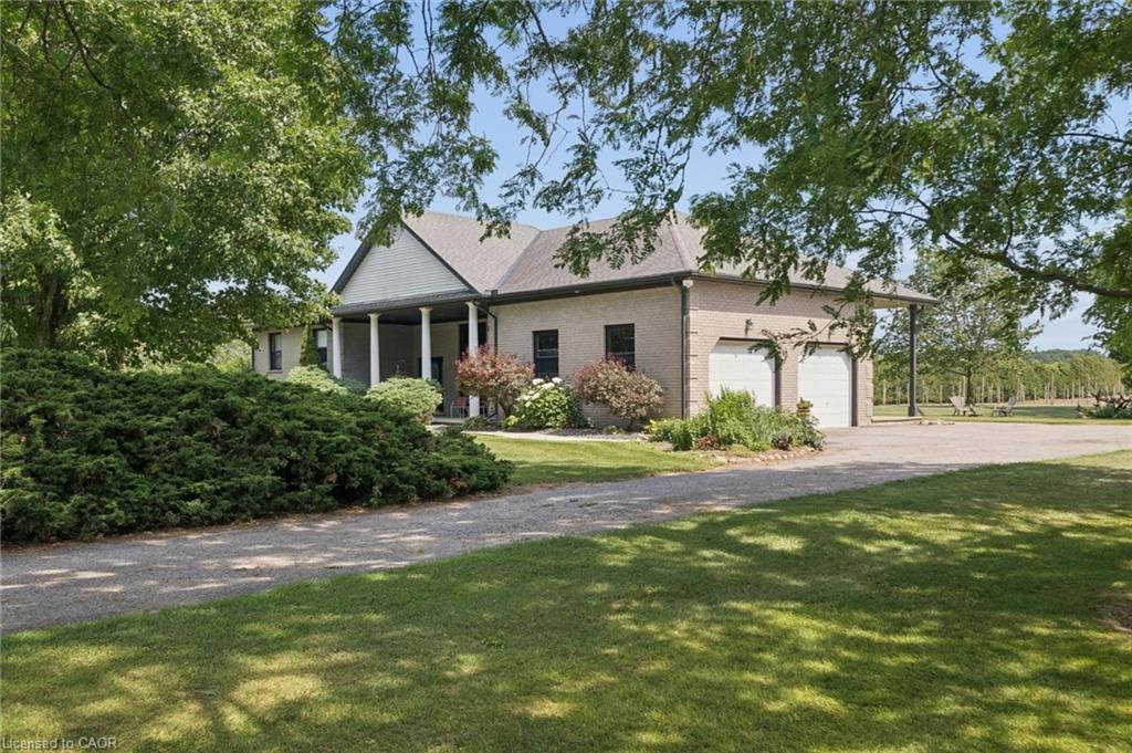 Brick exterior residence featuring a covered front porch with white columns, a two-car garage, and a gravel driveway