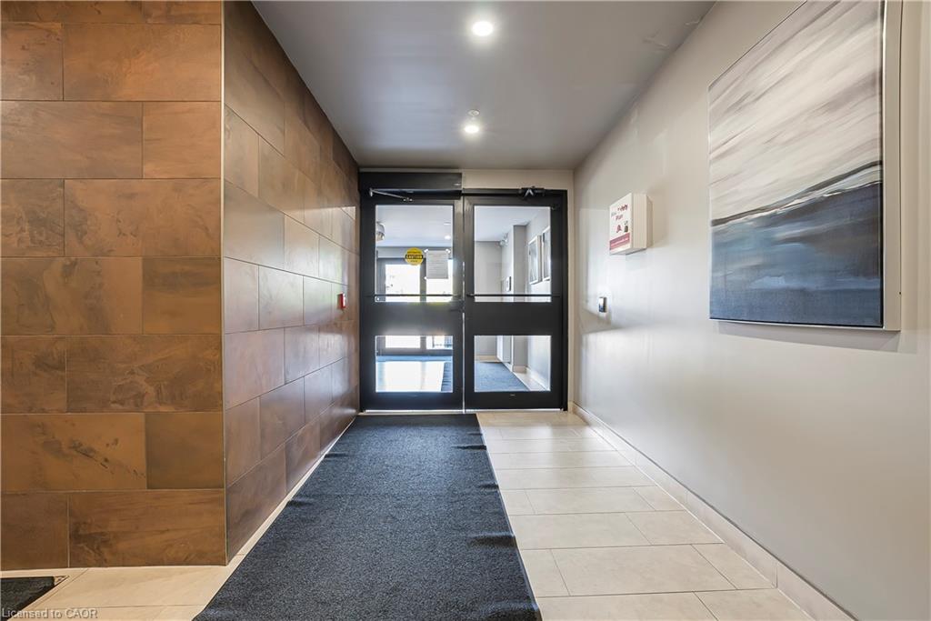 Entryway featuring automatic double glass doors, stone-look wall tiling, light neutral wall paint, and recessed ceiling lighting