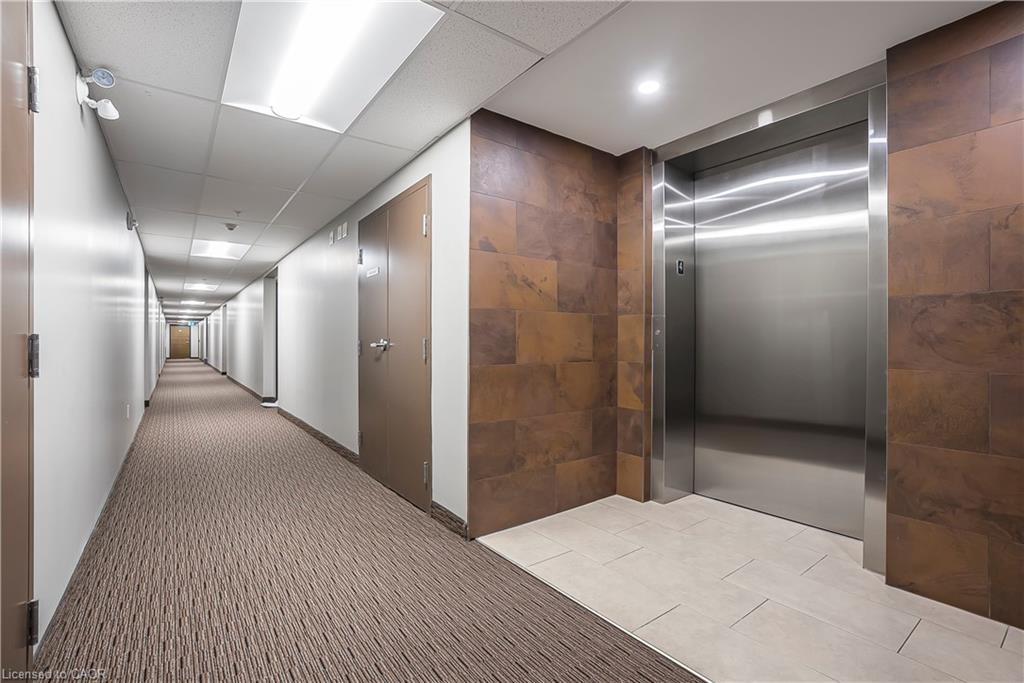 Elevator lobby featuring a stainless steel elevator, textured wall panels, recessed lighting, and tile flooring
