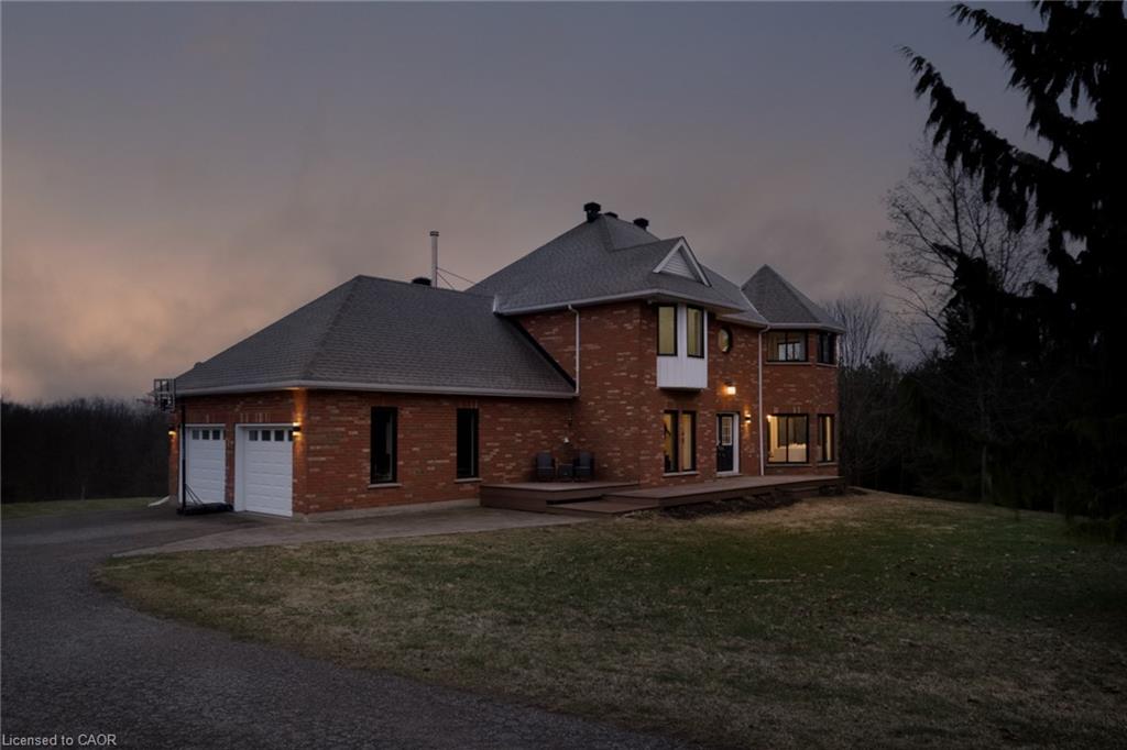 Brick exterior residence featuring a multi-gabled roofline, front-facing bay windows, a raised wood deck, and an attached two-car garage