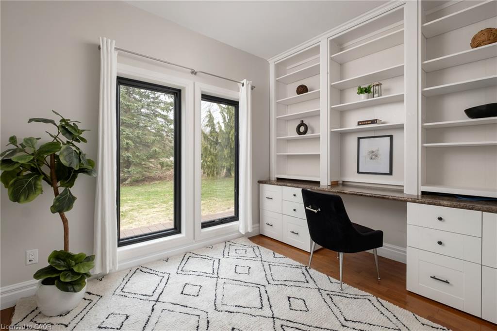 Built-in cabinetry with integrated desk space, wood-finish flooring, multiple windows with black trim, and extensive shelving