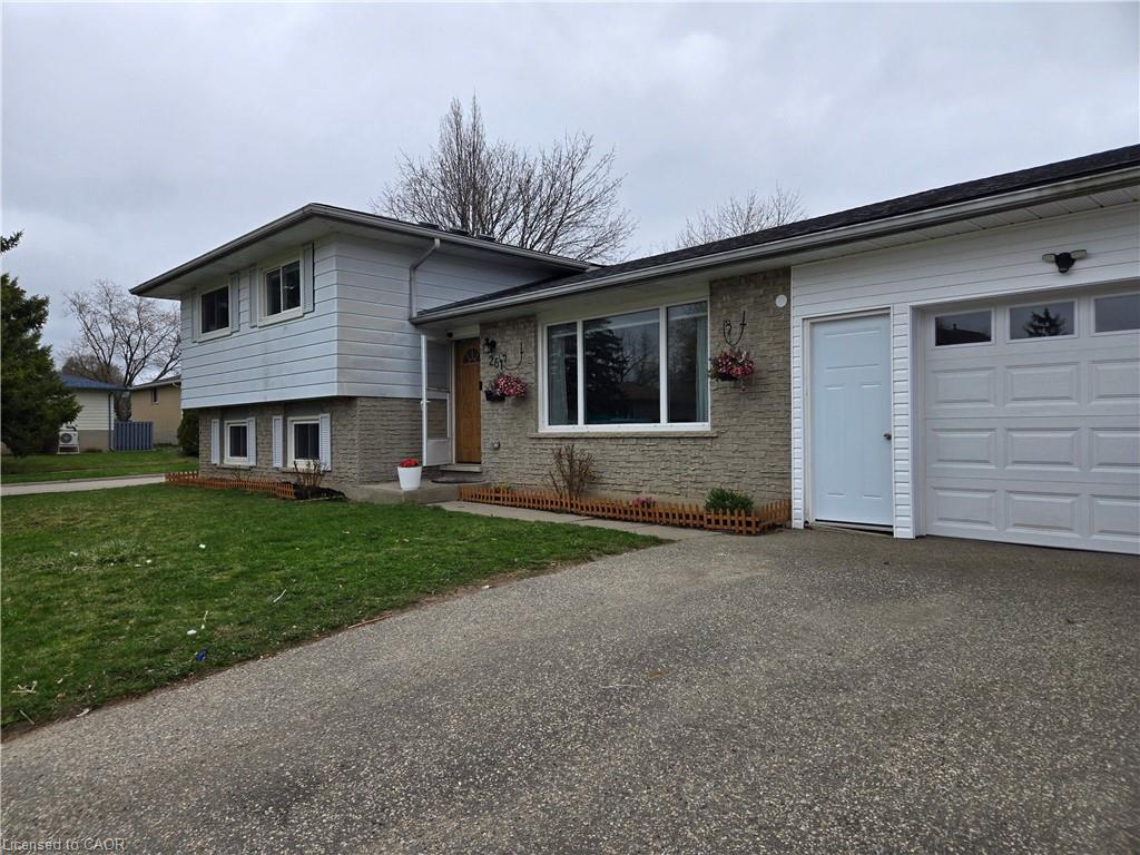 Split-level residence featuring a single-car garage with a panel door and upper window inserts
