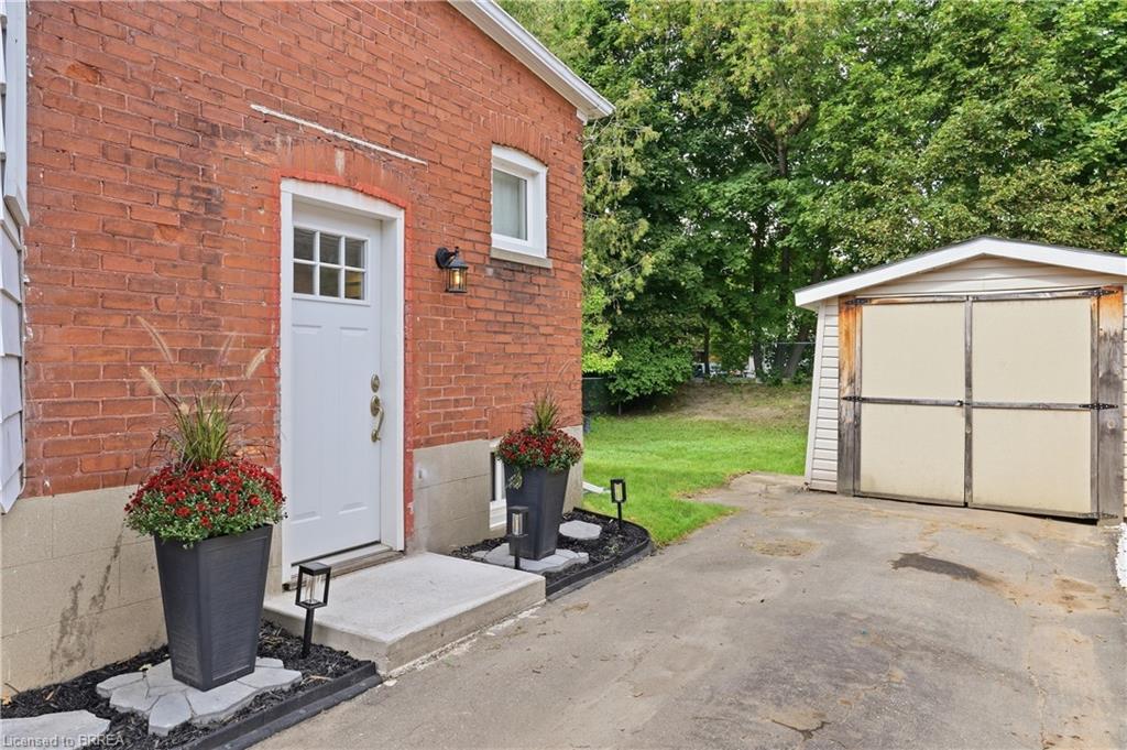 Brick exterior with white trim, concrete entry pad, and exterior lighting fixture