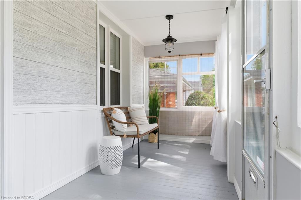 Enclosed porch with wide plank flooring, beadboard wainscoting, and a hanging light fixture