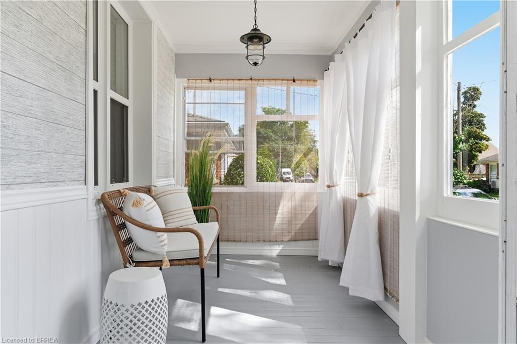 Enclosed porch featuring shiplap accent walls, wood-finish flooring, multiple windows, and a hanging light fixture