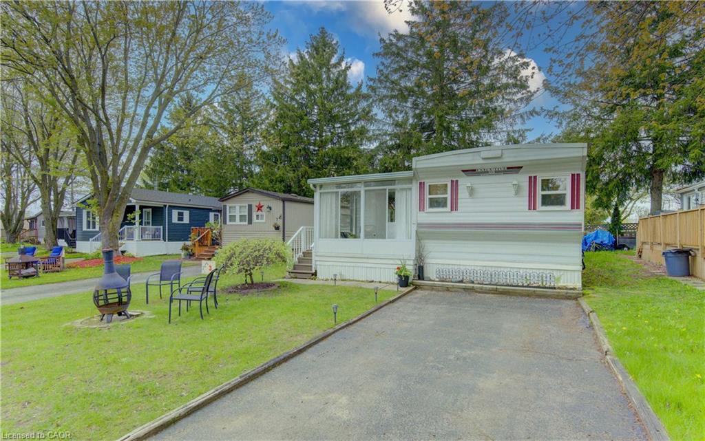 White siding exterior with red and white window shutters, featuring a driveway and a front yard with manicured lawn