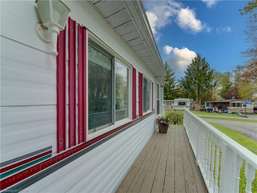 Exterior featuring white horizontal siding, red and white window shutters, and a white outdoor sconce