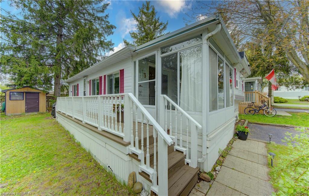White siding home featuring a screened-in porch with multiple windows, an extended open deck, and a separate storage shed in the backyard