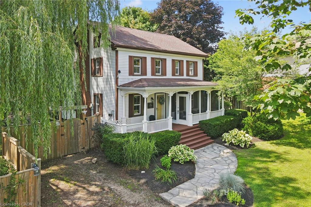 Two-story residence featuring white siding, brown window shutters, and a covered porch with white railings