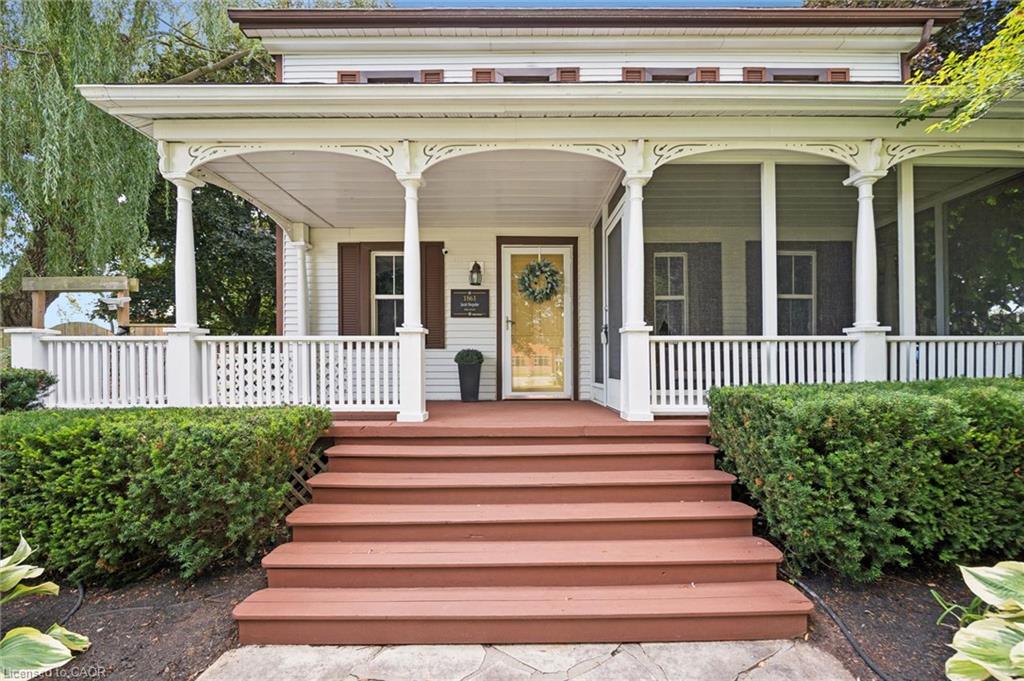 Expansive front porch featuring decorative columns, white railings, and a screened-in section