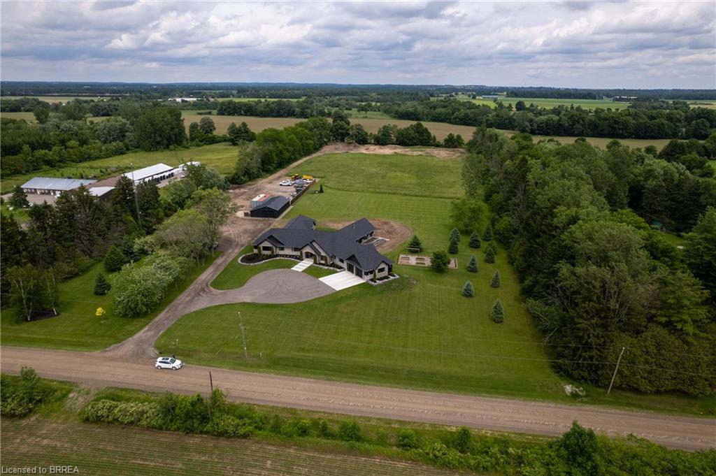 Expansive property featuring a modern ranch-style residence with a dark roof and light-colored exterior