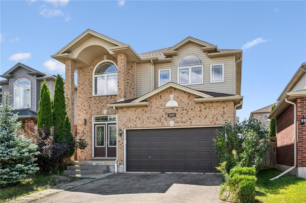 Brick and siding exterior with arched windows, prominent entry columns, and an integrated garage