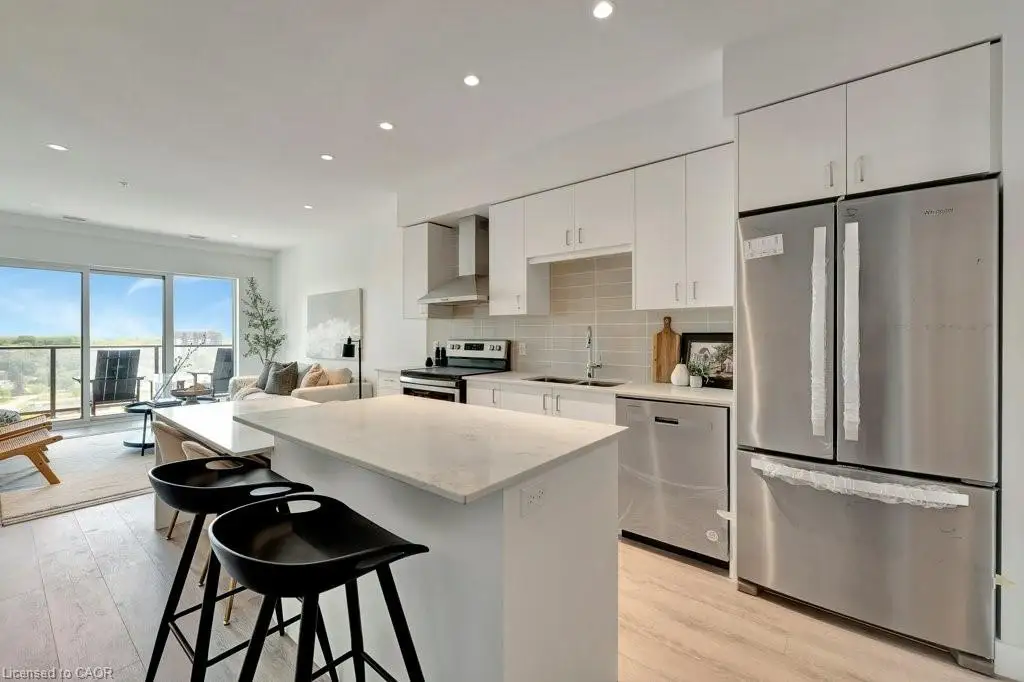 Kitchen featuring appliances with stainless steel finishes, wall chimney exhaust hood, a kitchen island, decorative backsplash, and light wood-style floors