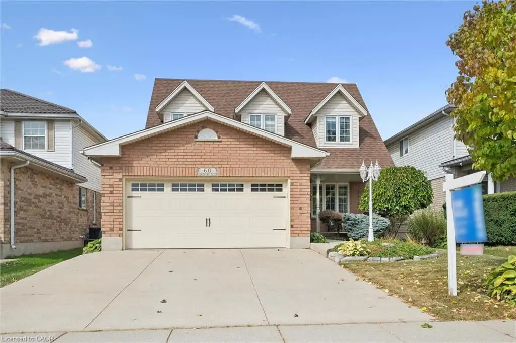 Brick exterior with a dormer roofline, an attached two-car garage, a concrete driveway, and established front landscaping