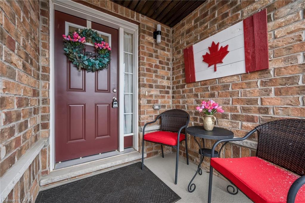 Brick facade entryway featuring a deep red paneled door with a decorative wreath, a sidelight window, and an overhead transom window