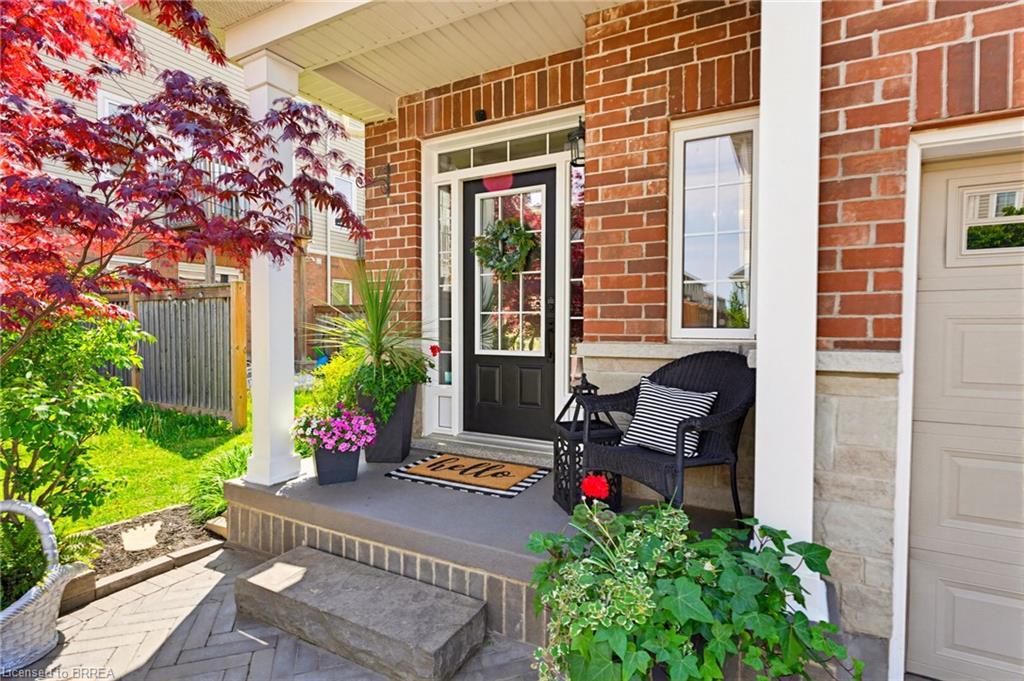 Brick exterior with stone accents, a covered front porch, and a paneled entry door with sidelights