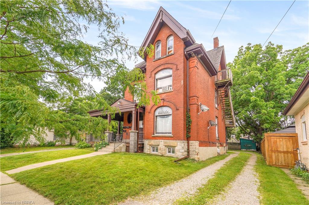 Brick multi-story residence featuring arched windows and a covered front porch
