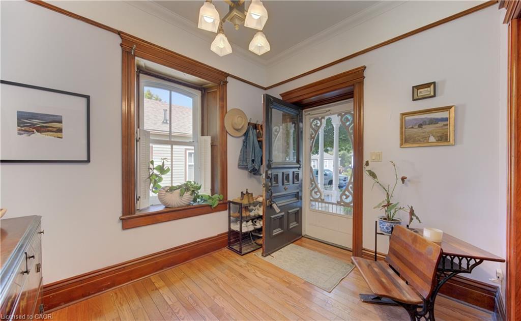 Hardwood flooring, ornate wood trim, classic white interior doors, and a decorative ceiling light fixture