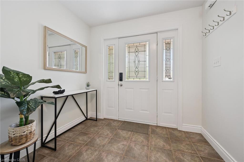 Front entry featuring a white panel door with decorative glass inserts, sidelites, and a tiled flooring